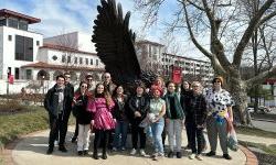 group of students stand together for photo in front of Red Hawk Statue